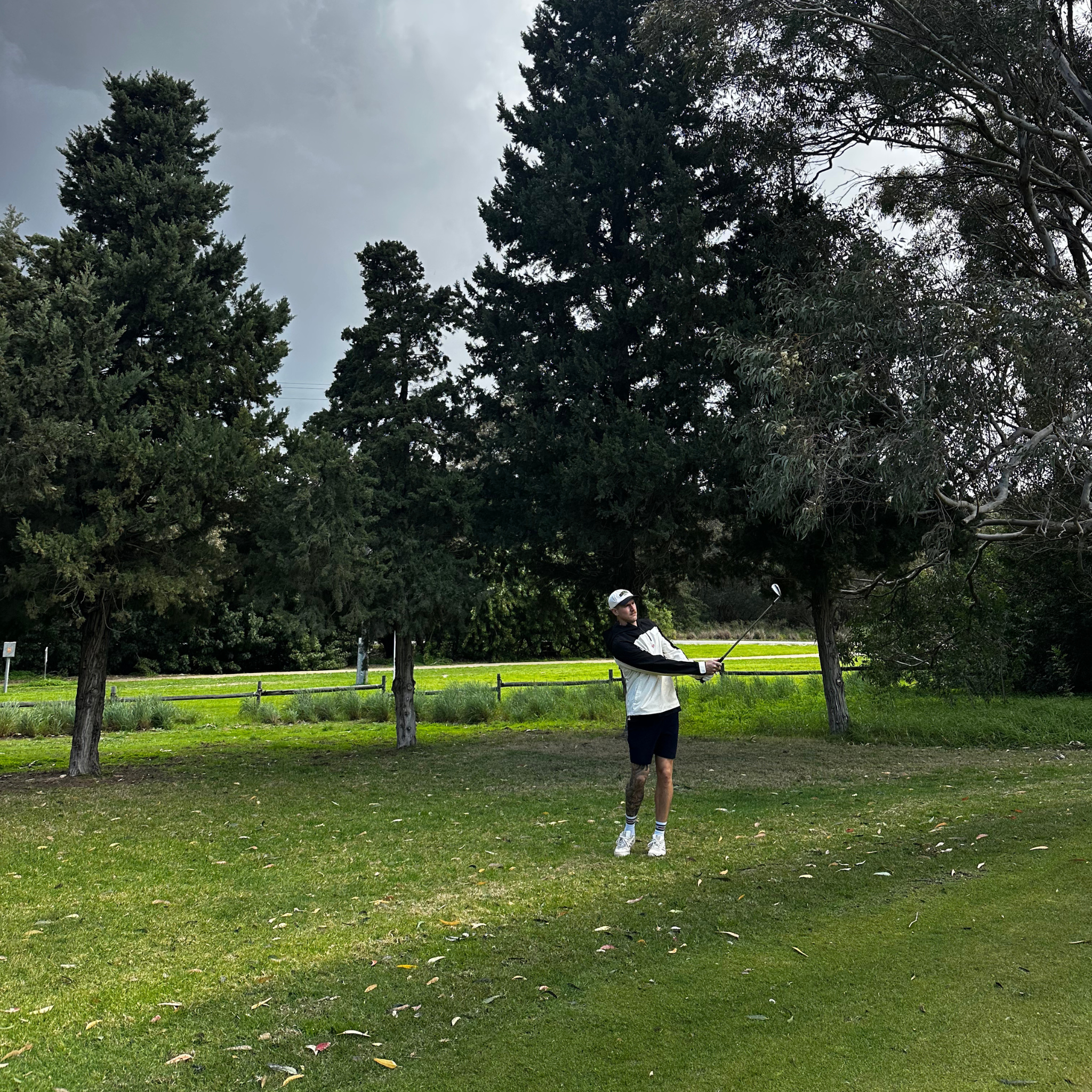 Person playing golf on a grassy field with trees in the background
